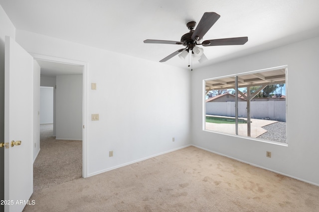 carpeted empty room featuring ceiling fan and baseboards