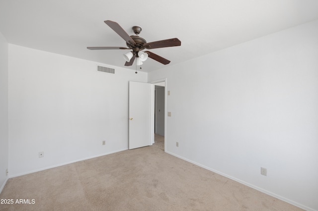spare room featuring light colored carpet, visible vents, baseboards, and ceiling fan