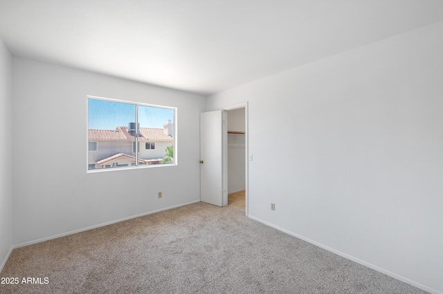 unfurnished bedroom featuring baseboards, carpet flooring, and a spacious closet