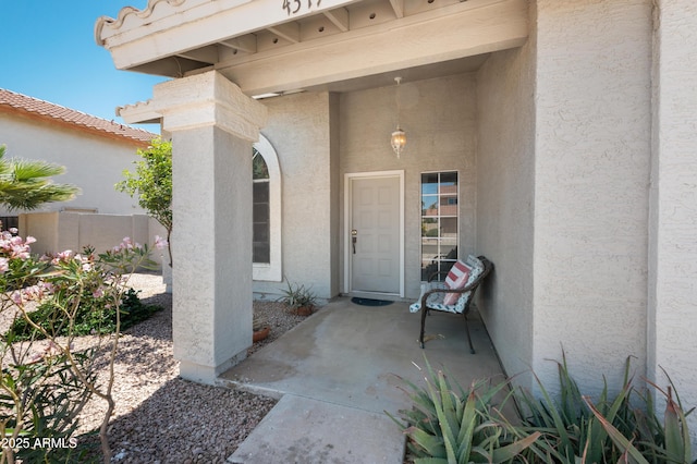 entrance to property with stucco siding and fence
