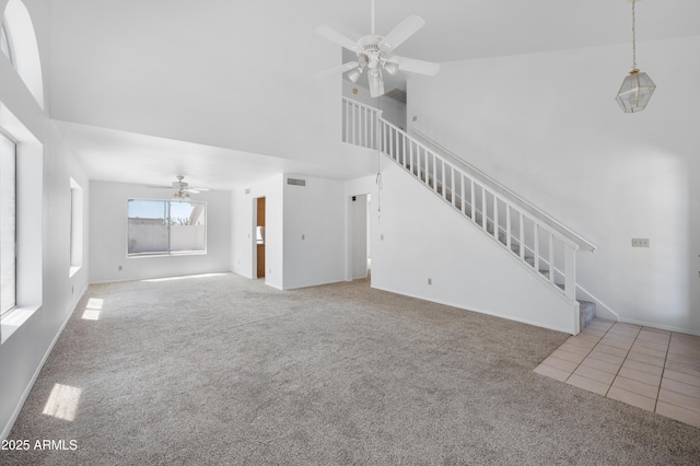 unfurnished living room with a ceiling fan, high vaulted ceiling, carpet floors, visible vents, and stairs