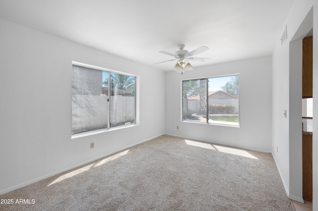 spare room featuring baseboards, ceiling fan, visible vents, and light colored carpet