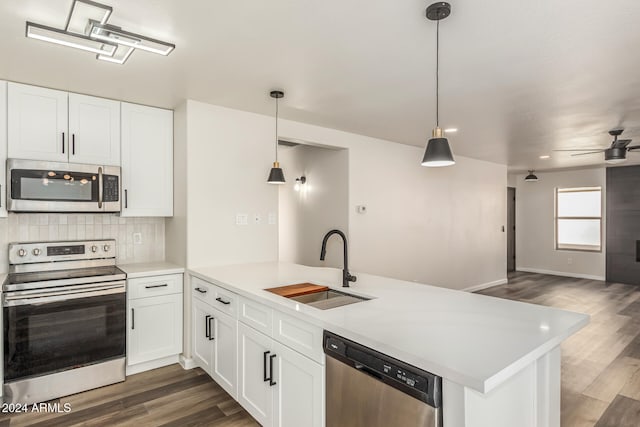 kitchen with kitchen peninsula, white cabinetry, sink, and appliances with stainless steel finishes