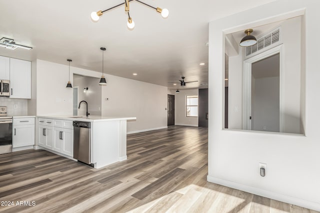 kitchen with white cabinets, ceiling fan with notable chandelier, sink, appliances with stainless steel finishes, and kitchen peninsula