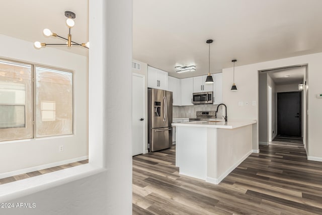 kitchen with kitchen peninsula, stainless steel appliances, white cabinetry, and dark wood-type flooring