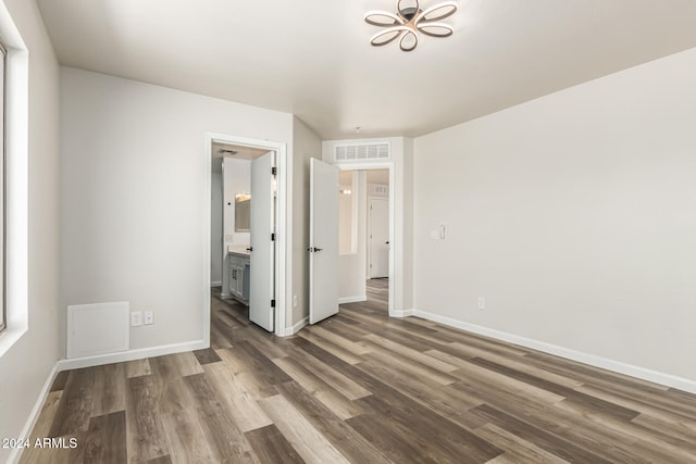 unfurnished bedroom with connected bathroom and dark wood-type flooring