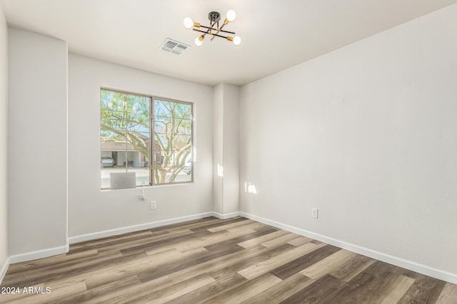 spare room featuring hardwood / wood-style flooring and an inviting chandelier