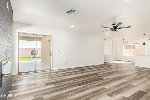 unfurnished living room featuring ceiling fan, a healthy amount of sunlight, and wood-type flooring