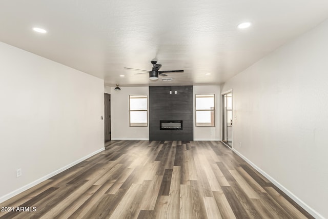 unfurnished living room with a tile fireplace, ceiling fan, and dark hardwood / wood-style floors