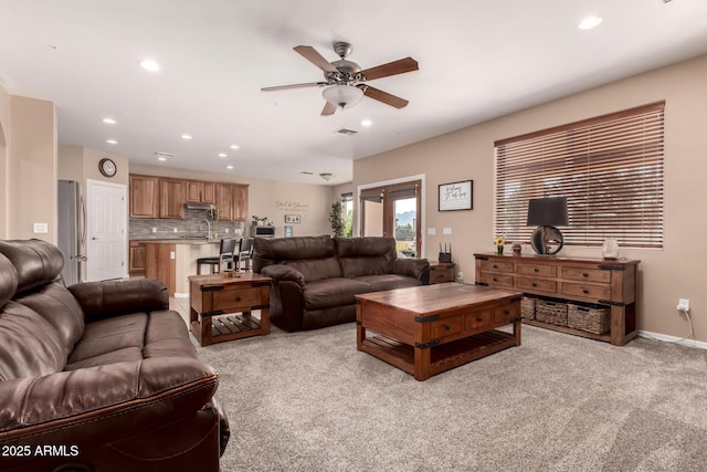 living room with sink, light colored carpet, and ceiling fan