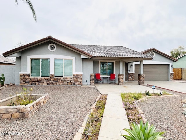 view of front of home featuring covered porch, stucco siding, concrete driveway, a garage, and stone siding