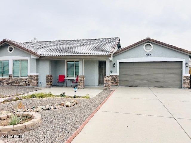 single story home with a porch, a garage, stone siding, and stucco siding