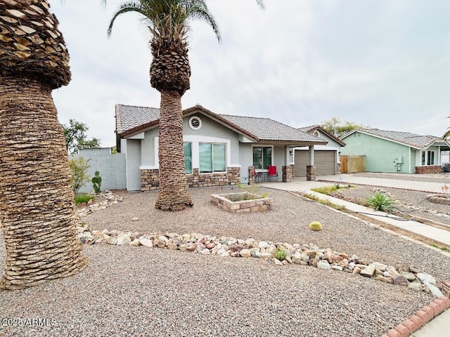 view of front of property featuring an attached garage, stucco siding, concrete driveway, stone siding, and a tile roof