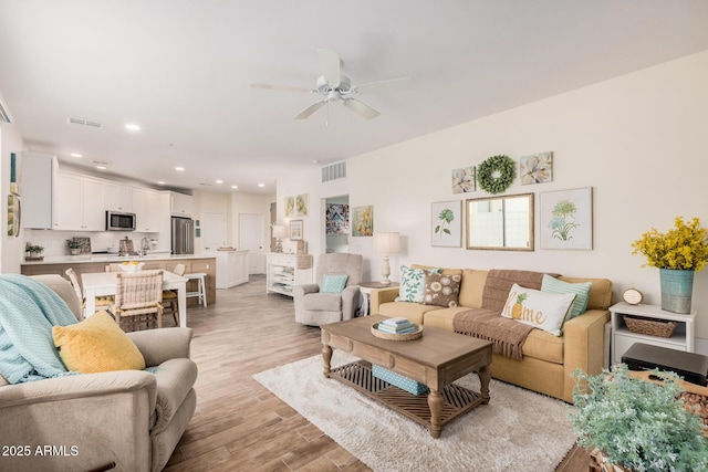 living room featuring ceiling fan and light hardwood / wood-style flooring