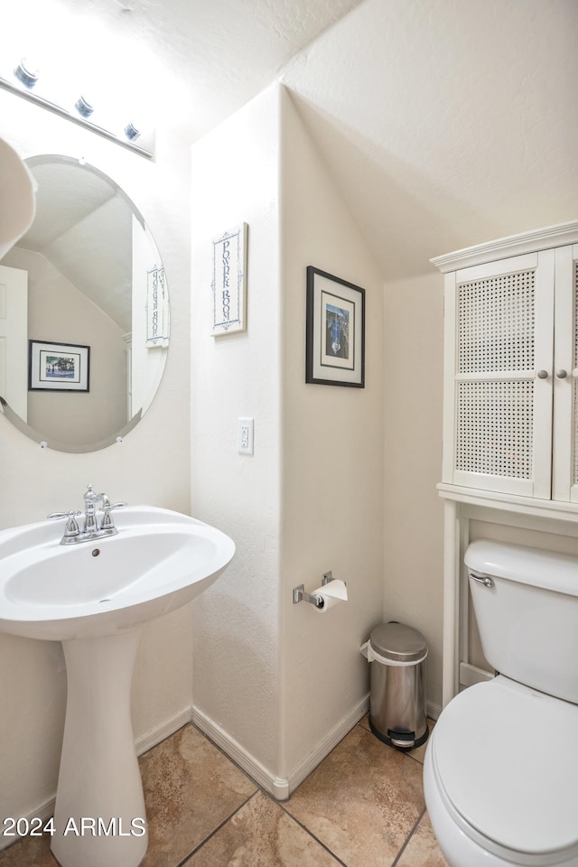 bathroom with sink, lofted ceiling, tile patterned flooring, and toilet