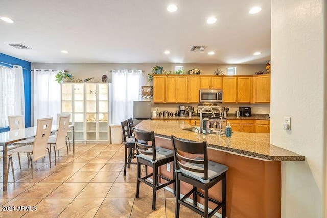 kitchen featuring light tile patterned floors, a kitchen breakfast bar, sink, and a wealth of natural light