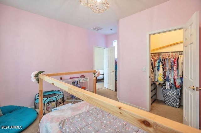 carpeted bedroom featuring a spacious closet, a closet, and a chandelier