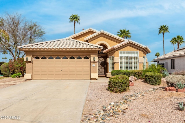 view of front of property with an attached garage, a tile roof, concrete driveway, and stucco siding