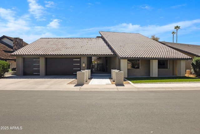 view of front of house with a garage, a tiled roof, concrete driveway, and brick siding