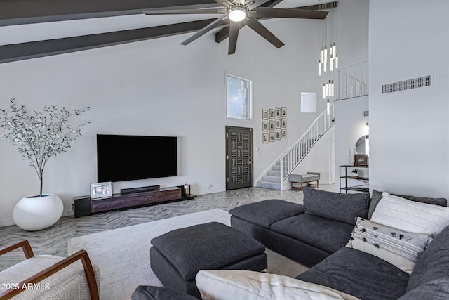 living room with a healthy amount of sunlight, visible vents, stairway, and a towering ceiling