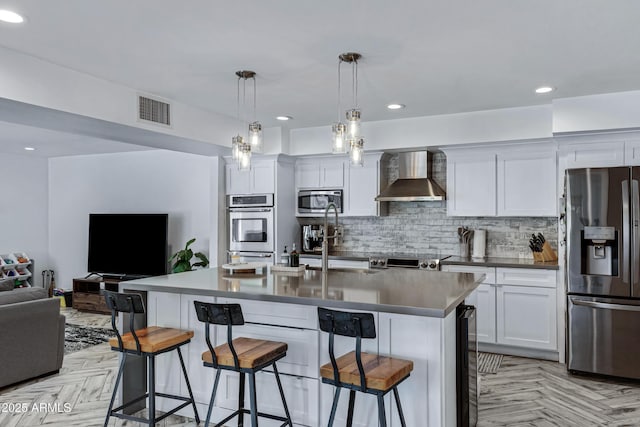 kitchen featuring visible vents, open floor plan, appliances with stainless steel finishes, backsplash, and wall chimney exhaust hood