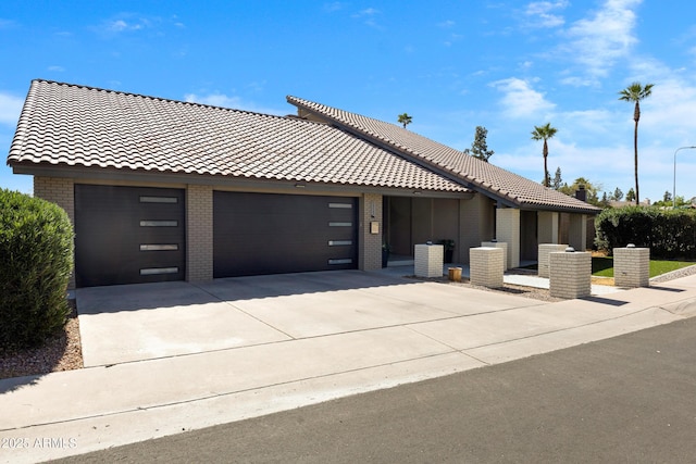 view of front of property with a garage, a tile roof, brick siding, and driveway