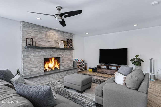 living room featuring ceiling fan, a stone fireplace, wood finished floors, and recessed lighting