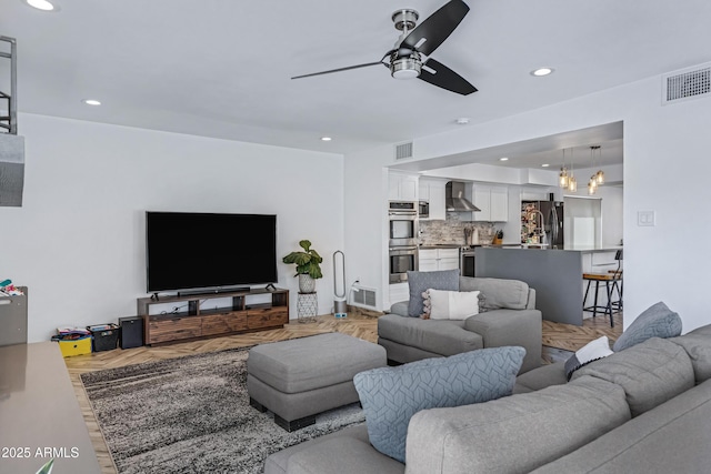 living room with a ceiling fan, visible vents, and recessed lighting