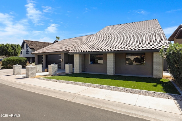 view of front facade with a front yard, brick siding, and a tiled roof