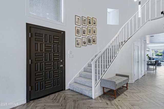 entrance foyer with a towering ceiling, stairs, and baseboards