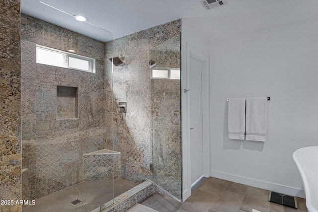 full bath featuring a stall shower, visible vents, a freestanding bath, and baseboards