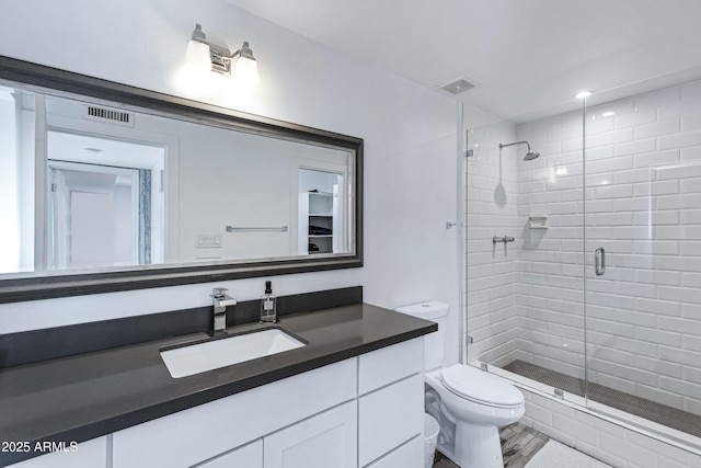 bathroom with toilet, a stall shower, visible vents, and vanity