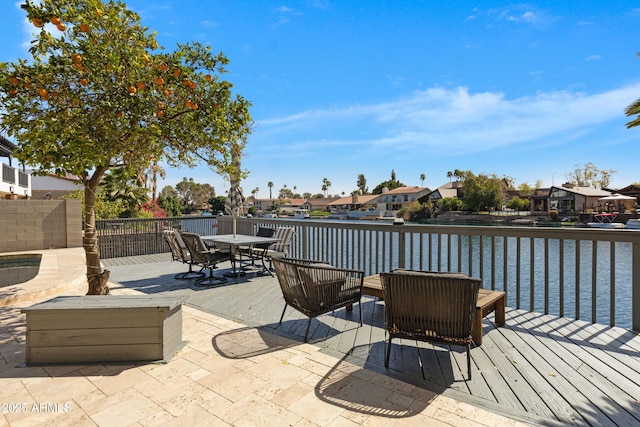 view of patio featuring a residential view, a deck with water view, and outdoor dining space