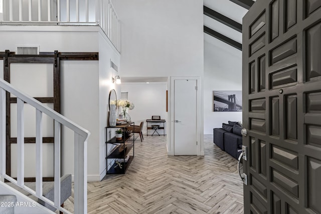 foyer entrance featuring a high ceiling, stairway, and visible vents