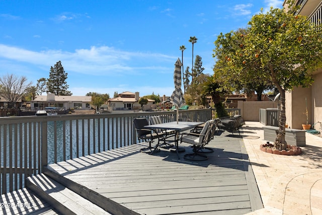 deck with outdoor dining area, a water view, and a residential view