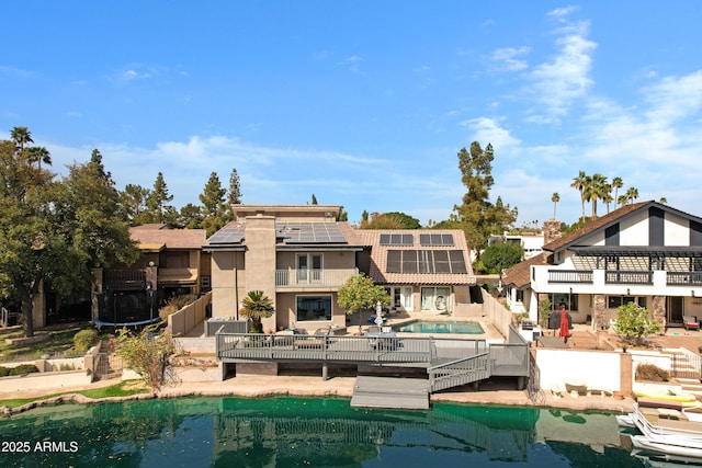 rear view of house featuring an outdoor pool, a patio, a balcony, and solar panels