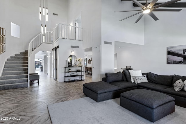 living area with stairway, ceiling fan, visible vents, and a barn door