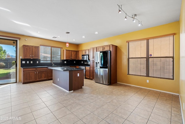 kitchen featuring pendant lighting, a center island, stainless steel appliances, backsplash, and light tile patterned floors