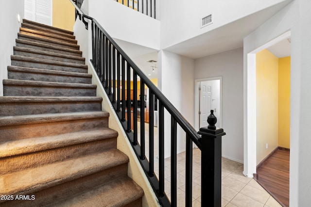 stairs featuring tile patterned floors and a towering ceiling