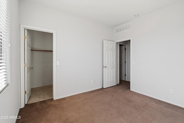 unfurnished bedroom with a walk in closet, carpet flooring, and a closet