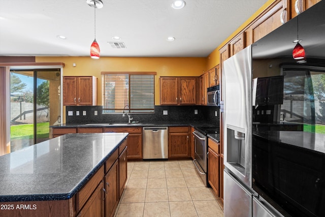 kitchen with pendant lighting, appliances with stainless steel finishes, sink, backsplash, and light tile patterned floors