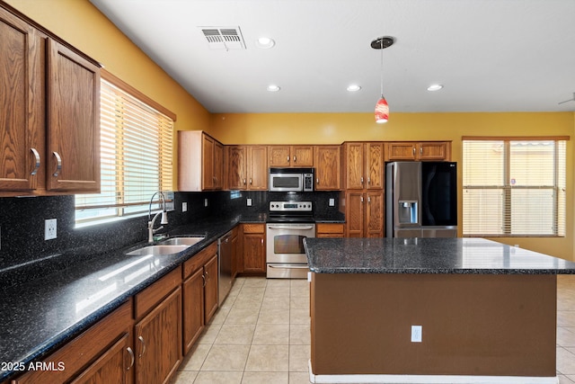 kitchen featuring pendant lighting, sink, light tile patterned floors, a center island, and stainless steel appliances