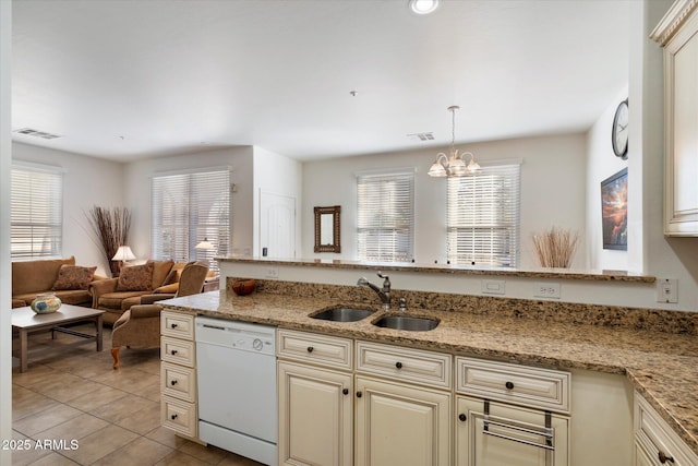 kitchen featuring dishwasher, pendant lighting, light stone counters, sink, and cream cabinets