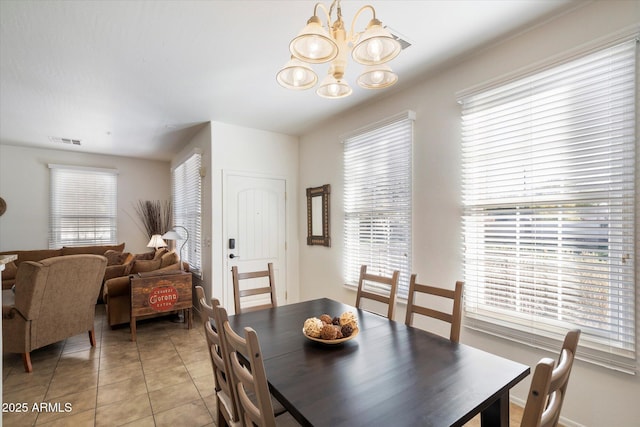 tiled dining space featuring a wealth of natural light and a notable chandelier