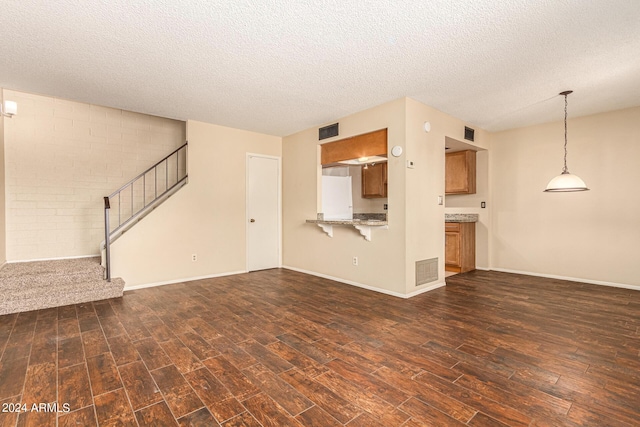 unfurnished living room with a textured ceiling, stairs, visible vents, and dark wood-style flooring