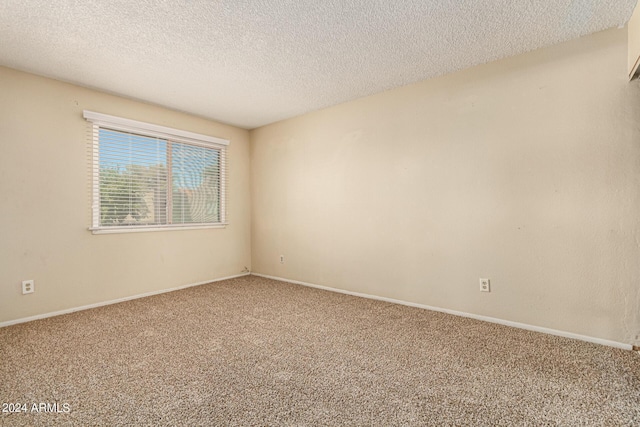 empty room featuring carpet, baseboards, and a textured ceiling