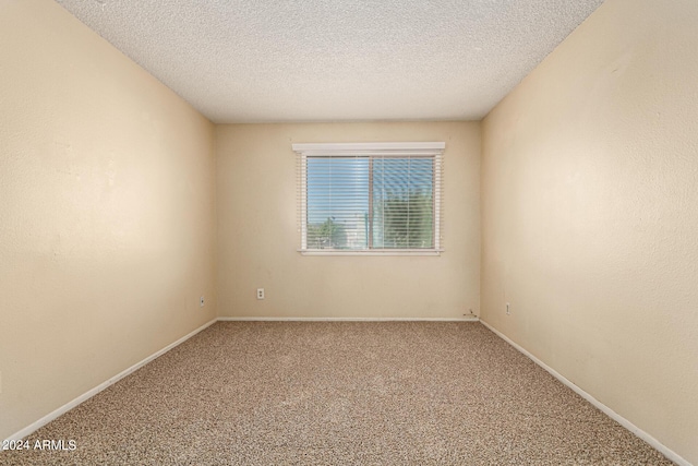 carpeted spare room with a textured ceiling and baseboards