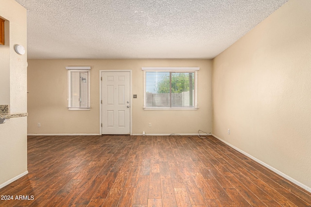 spare room featuring baseboards, dark wood finished floors, and a textured ceiling