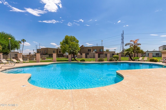 community pool with a patio area and fence