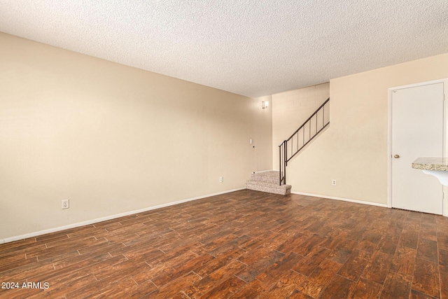 unfurnished room with wood finished floors, a textured ceiling, and stairs